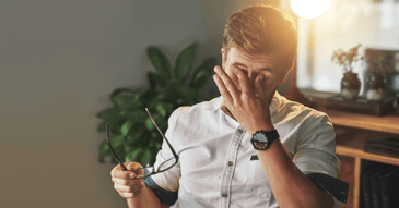 Tired professional at a desk rubbing eyes
