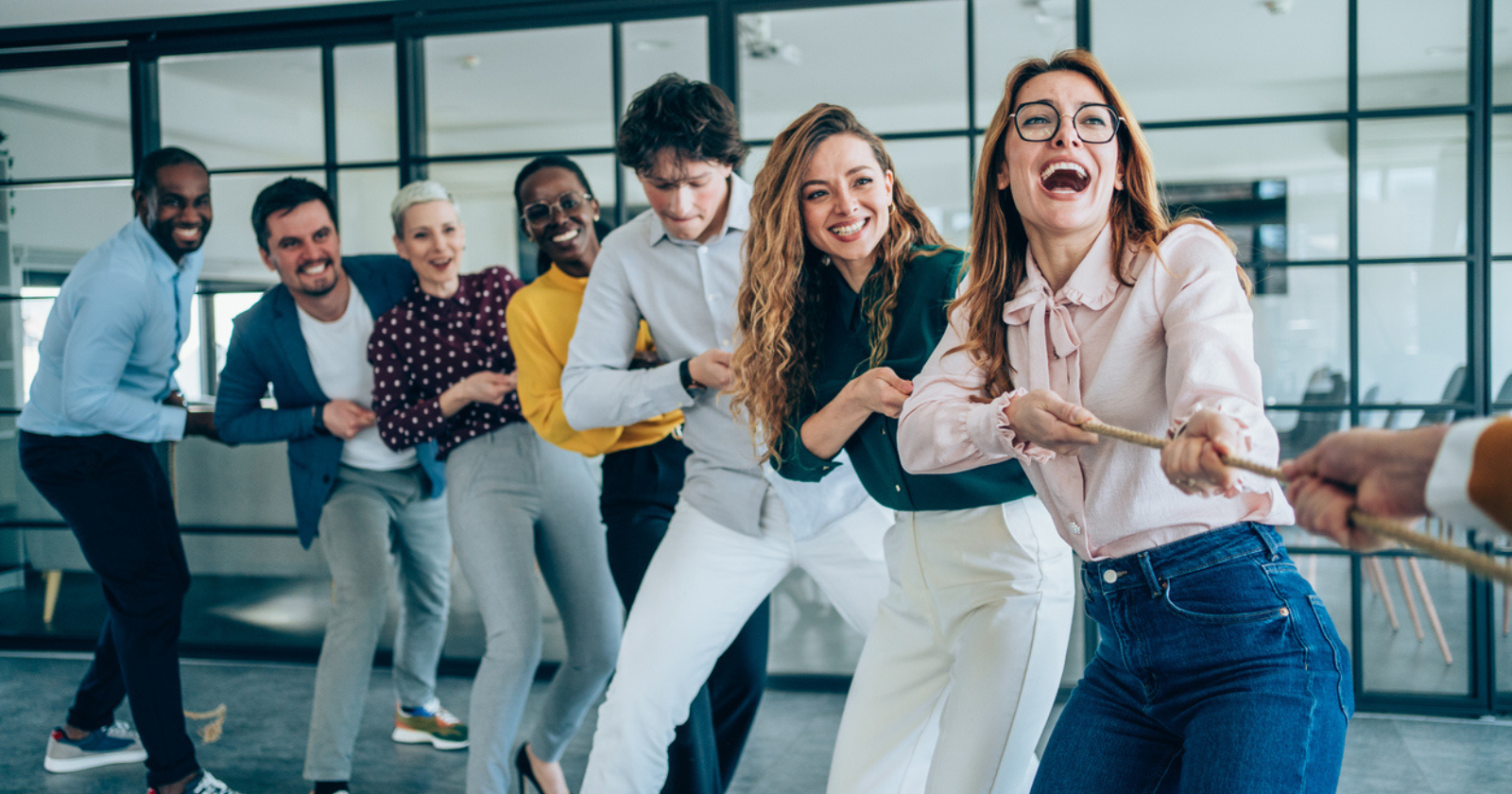 Colleagues playing tug of war in a modern office, showcasing teamwork, competition, and team building